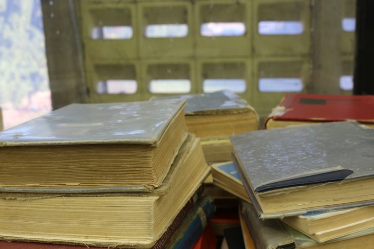 Un grupo de libros permanece agrupado a un lado de los ventanales del edificio Central de Bibliotecas UdeC