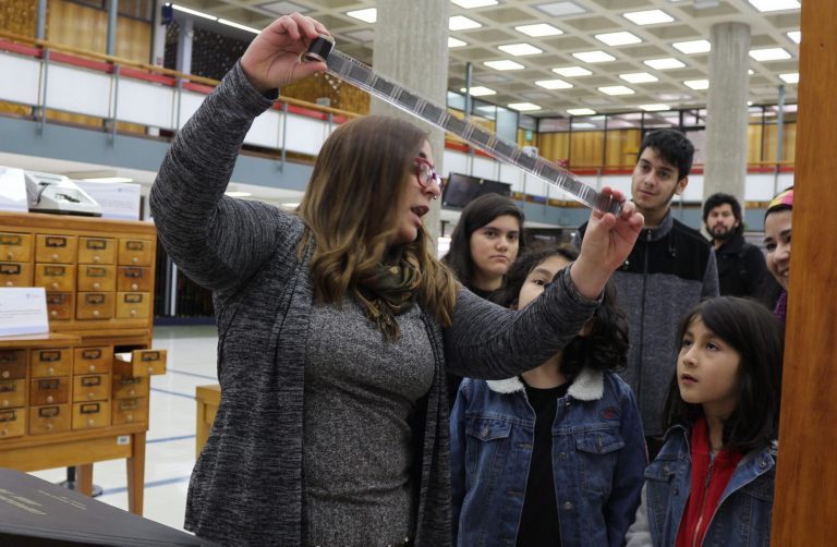 La Jefa de Sala Chile, Rose Marie Espinoza, muestra a visitantes una antigua cinta de fotografías.