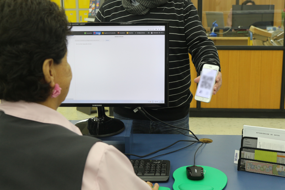 Estudiante muestra celular a integrante del equipo de Bibloiotecas UdeC con el nuevo código QR