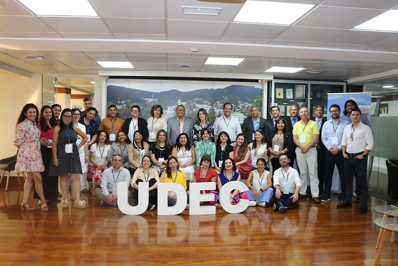 Foto grupal de todos los asistentes al encuentro de FOLIO, quienes se encuentran detrás de unas letras gigantes que forman el nombre UdeC