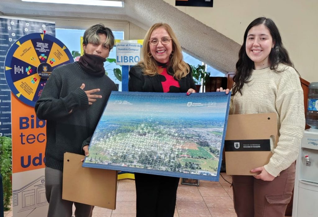 Ganador y ganadora del "Rompecabezas gigante" junto a Directora de la Biblioteca del Campus Chillán