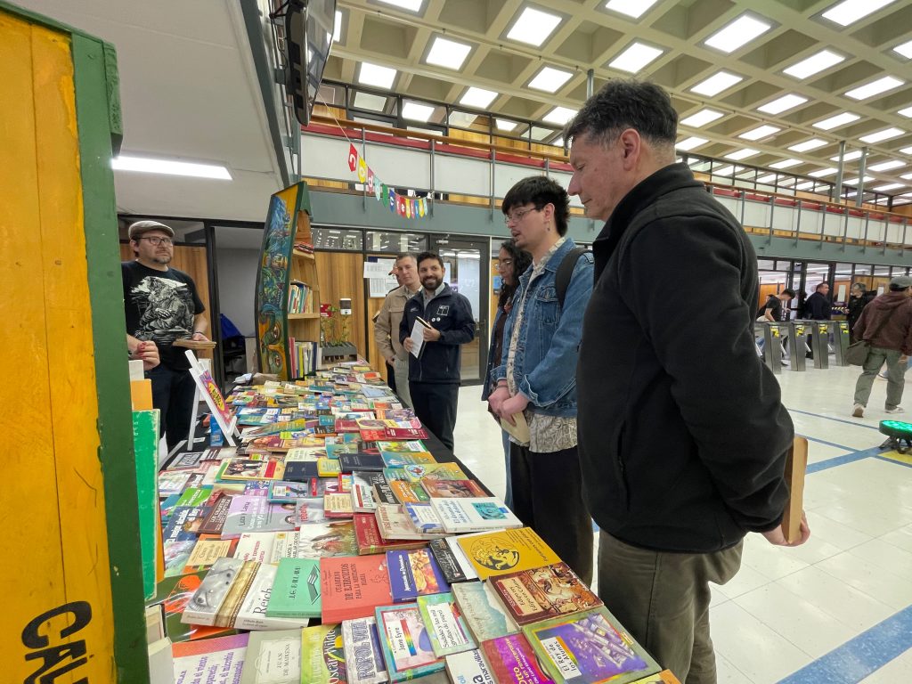 Director de UdeC+Sustentable y Vicepresidente FEC observan stand de libros en la Biblioteca Central