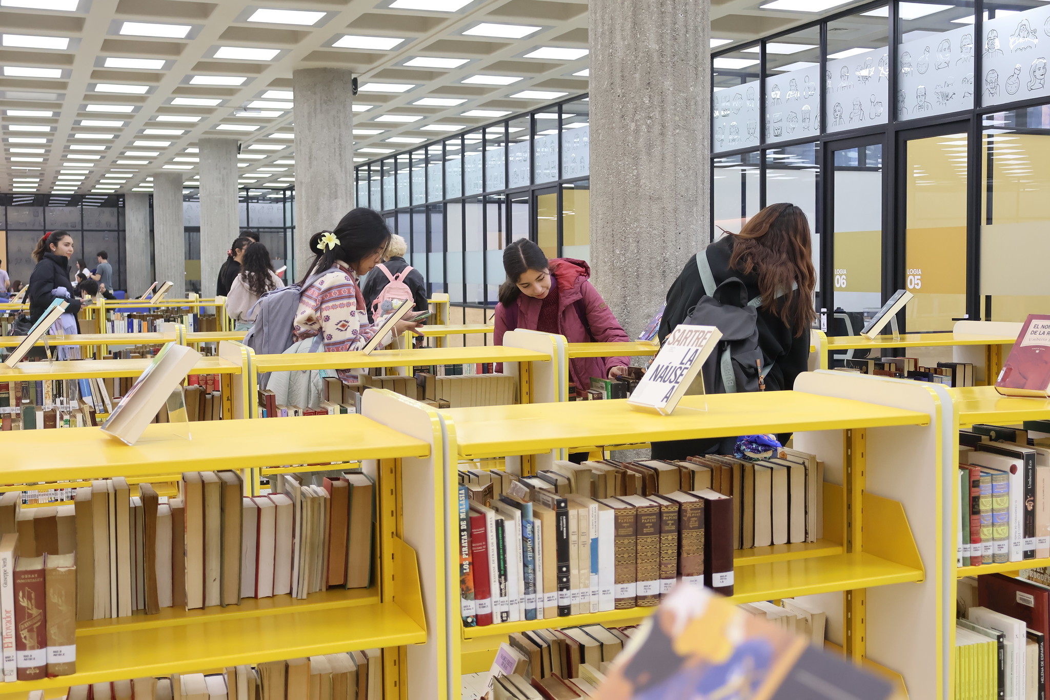 Estudiantes observan estanterías de libros en el renovado cuerto piso de la Biblioteca Central.