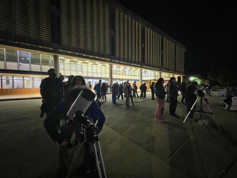 Asistentes a observación astronómica miran a través de telescopio en explanada de la Biblioteca Central UdeC.