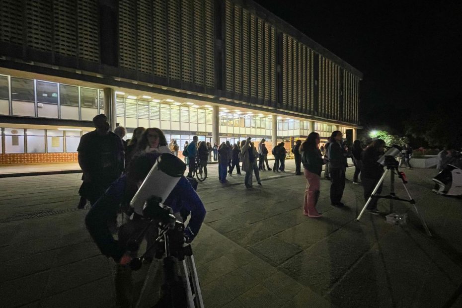 Asistentes a observación astronómica miran a través de telescopio en explanada de la Biblioteca Central UdeC.