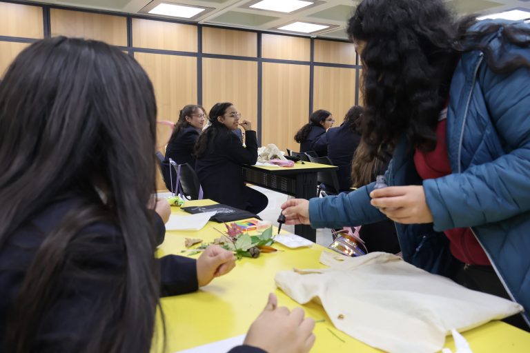 Tallerista explica cómo realizar eco-marcapáginas a estudiantes.