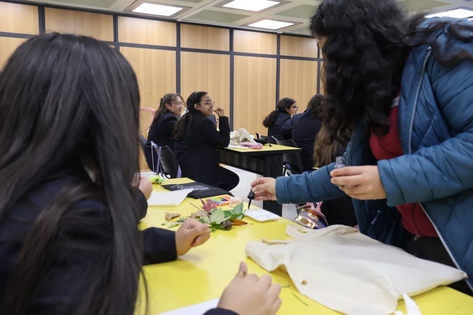 Tallerista explica cómo realizar eco-marcapáginas a estudiantes.