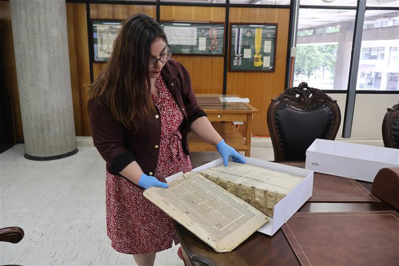 Jefa de Sala Chile, Rose Marie Espinoza, revisa incunable que resguarda la Universidad de Concepción.