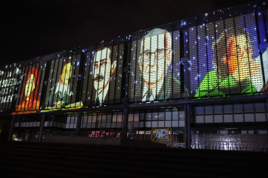 Una serie de rostros son proyectados en la fachada de la Biblioteca Central UdeC durante videomapping