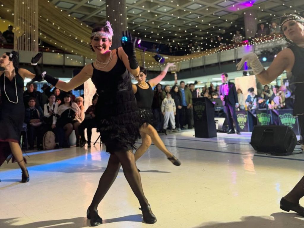 Estudiante caracterizada a la usanza de los años 20 del siglo XX baila en hall de la Biblioteca Central