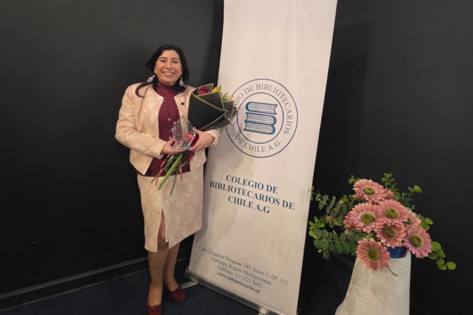 Directora de Bibliotecas UdeC, Karen Jara Maricic, sostiene un ramo de flores entregado tras premiación como Bibliotecaria Destacada