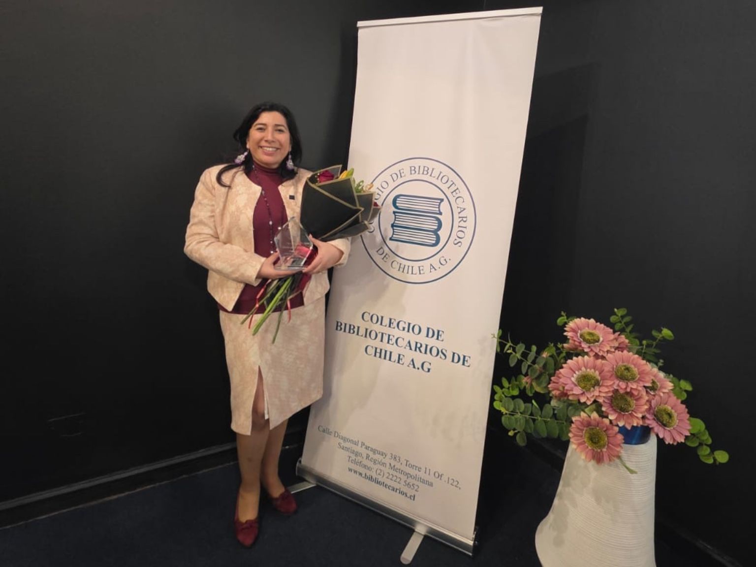 Directora de Bibliotecas UdeC, Karen Jara Maricic, sostiene un ramo de flores entregado tras premiación como Bibliotecaria Destacada