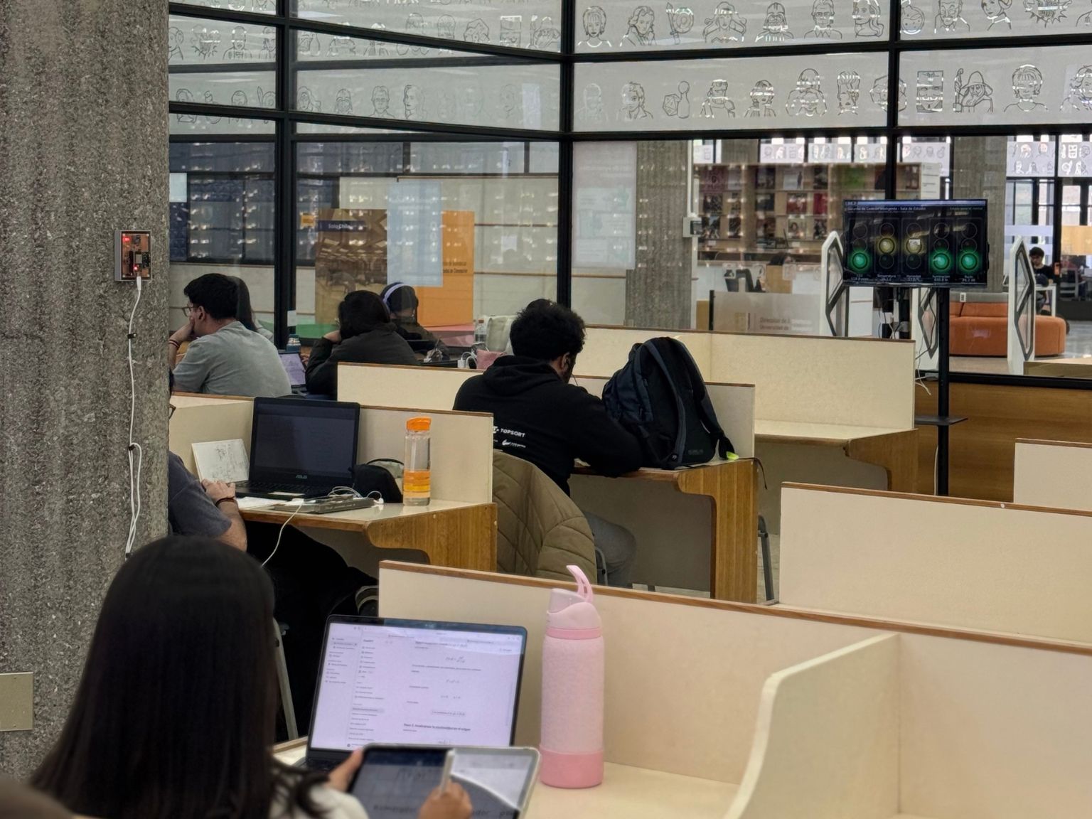 Un grupo de estudiantes ocupa una de las salas del cuarto piso de la Biblioteca Central, al fondo se ve el monitor que indica la medición del semáforo ambiental