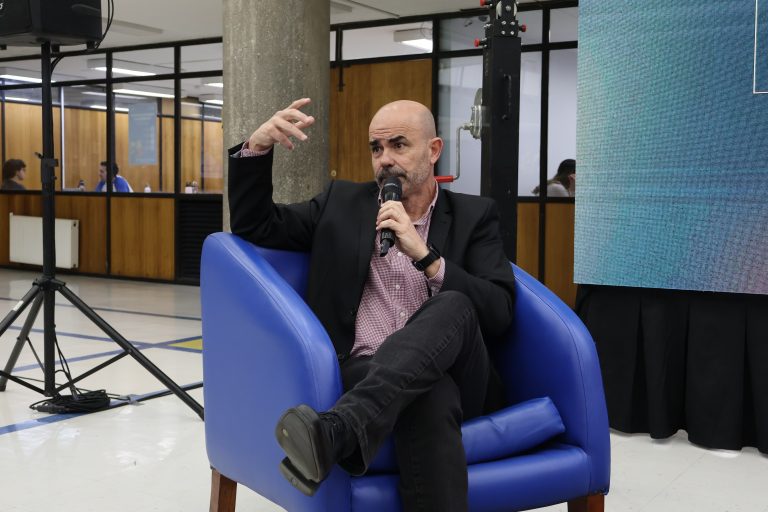 Escritor Eduardo Sacheri sostiene micrófono mientras conversa con el público presente en el hall de la Biblioteca Central durante encuentro literario