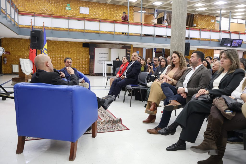 Escritor Eduardo Sacheri sostiene micrófono mientras conversa con el público presente en el hall de la Biblioteca Central durante encuentro literario