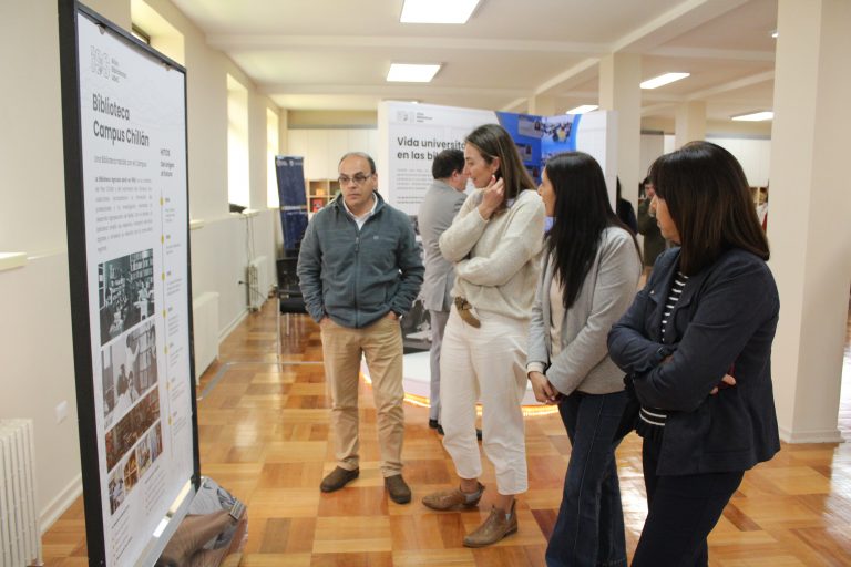 Asistentes observan paneles en el segundo piso de la Biblioteca del Campus Chillán