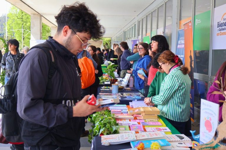 Estudiante observa libros en stand de la Dirección de Bibliotecas ubicado en pasillo de la Facultad de Ciencias Químicas